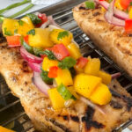 Close up photo of grilled fish with mango salsa on top