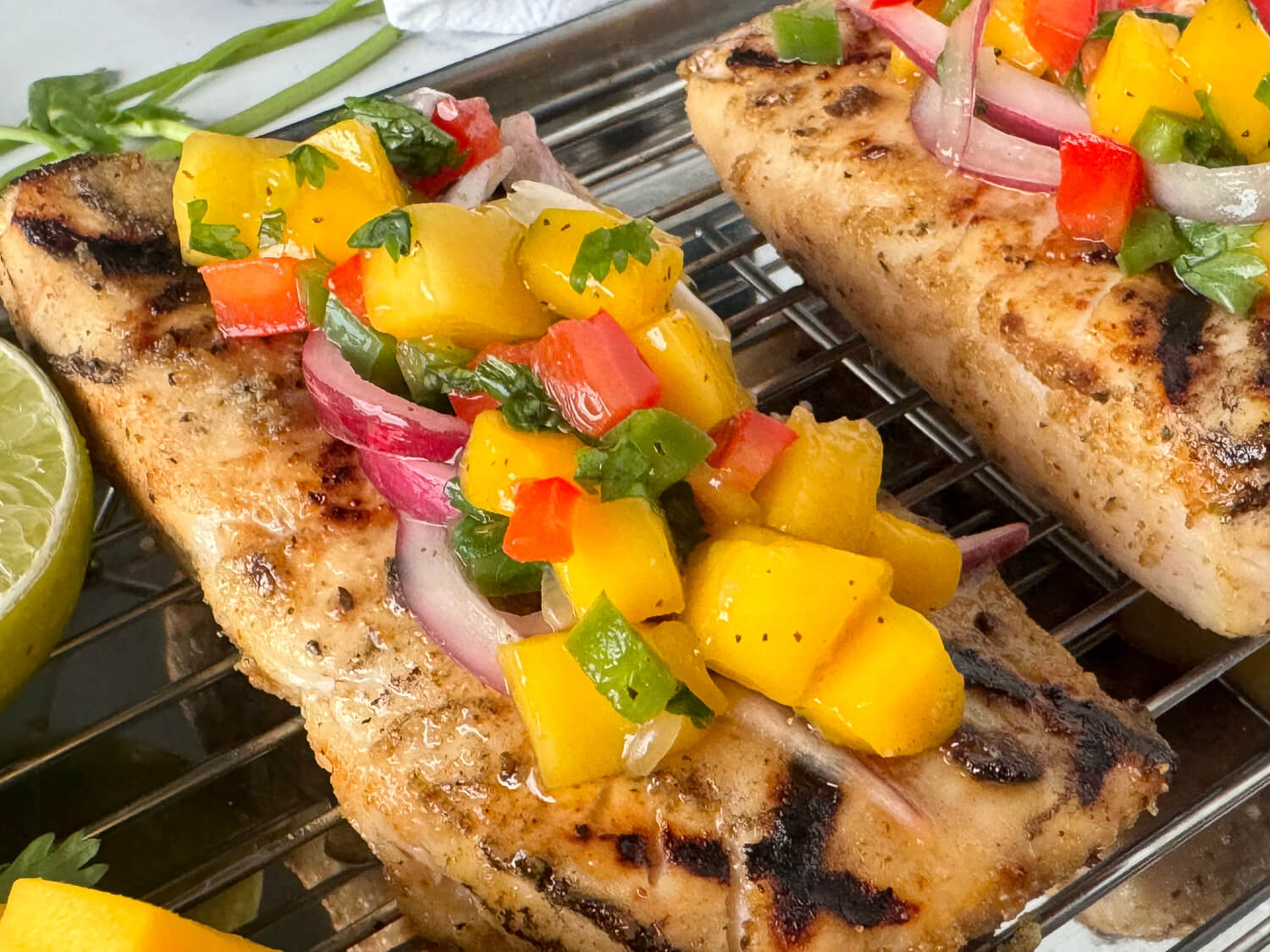 Close up photo of grilled fish with mango salsa on top