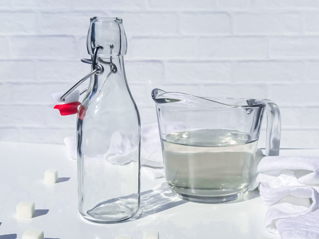 an open container next to simple syrup in a glass measuring cup
