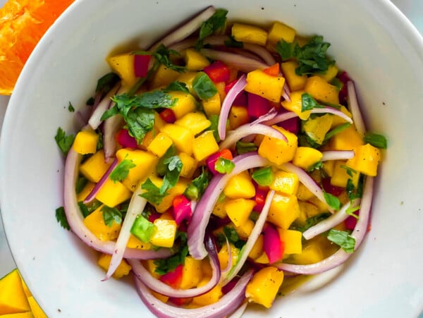 close up photo of mango salsa in a white bowl