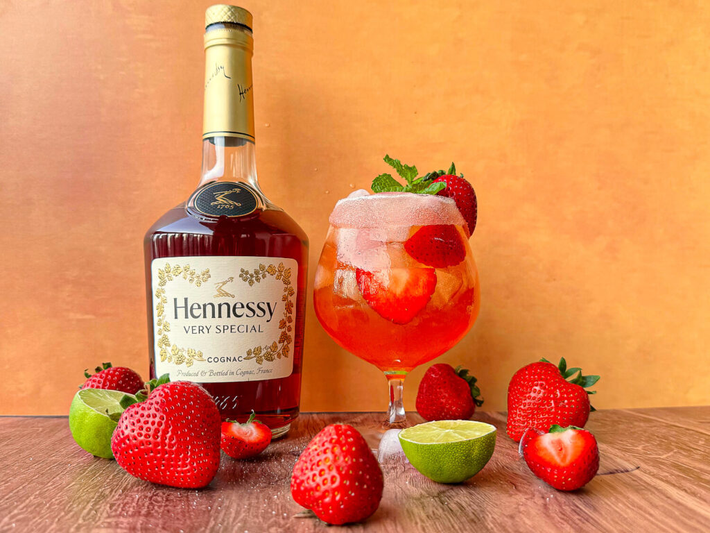 Photo of strawberry Hennessy Margarita next to a bottle of Hennessy cognac