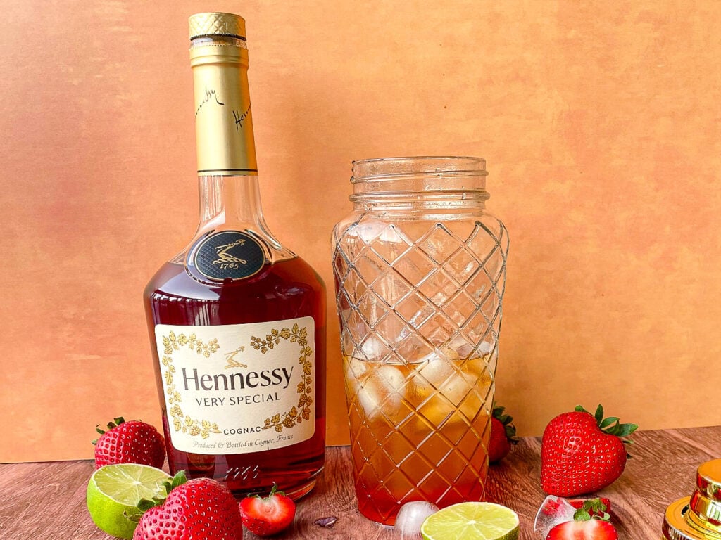 Photo of a Strawberry Hennessy Margarita in a cocktail shaker next to a bottle of Hennessy