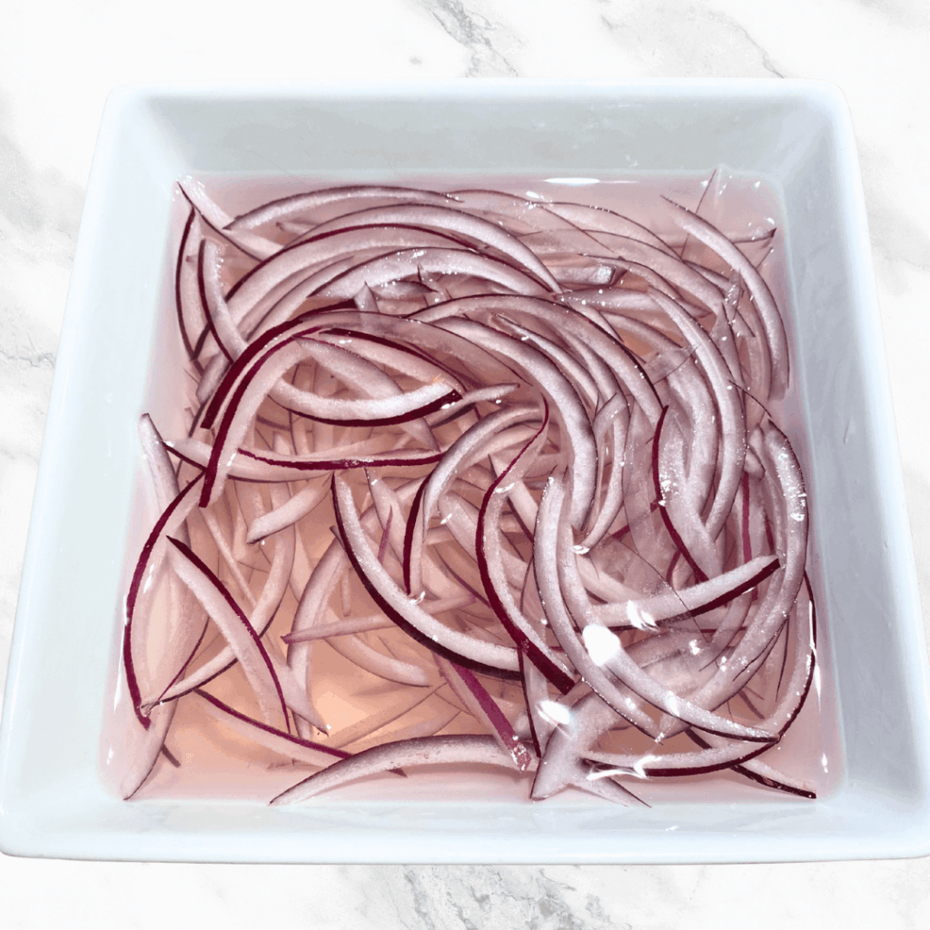 photo of red onions soaking in a white bowl