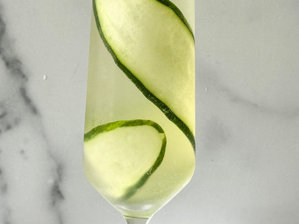 Close up photo of a cucumber ribbon in a champagne flute