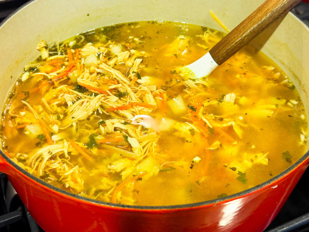 Photo of diced potatoes being added to chicken noodle soup