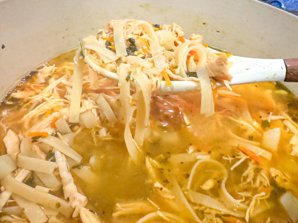 photo of noodles being added to chicken noodle soup