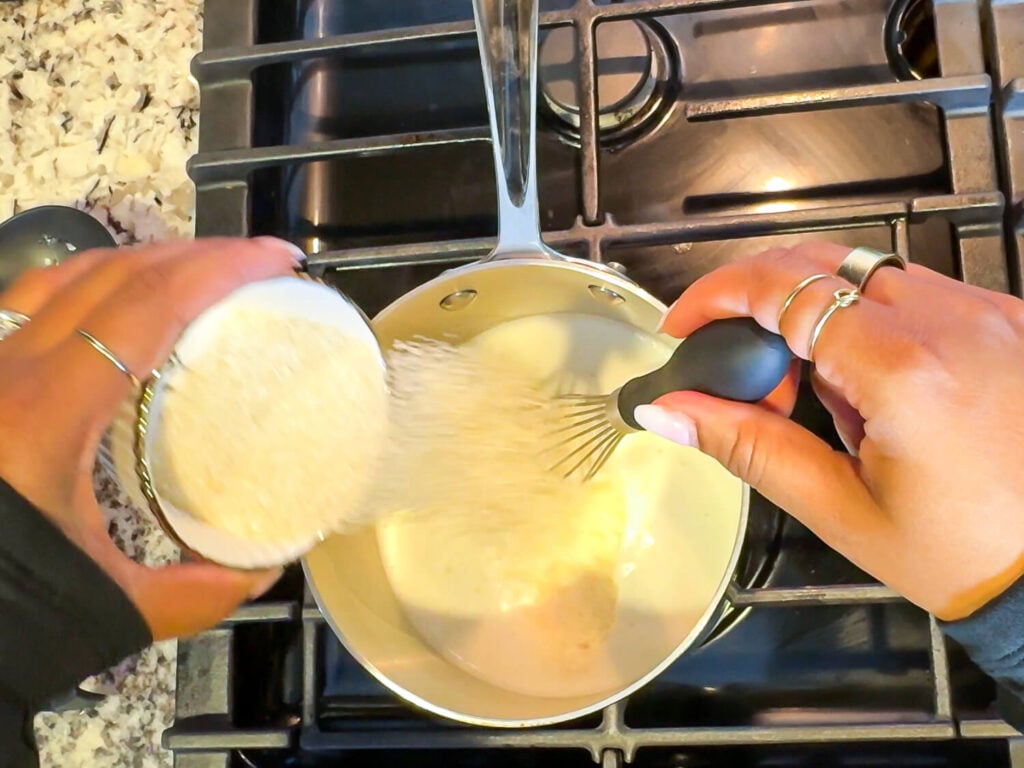 photo of pouring grits in a sauce pan with whisk