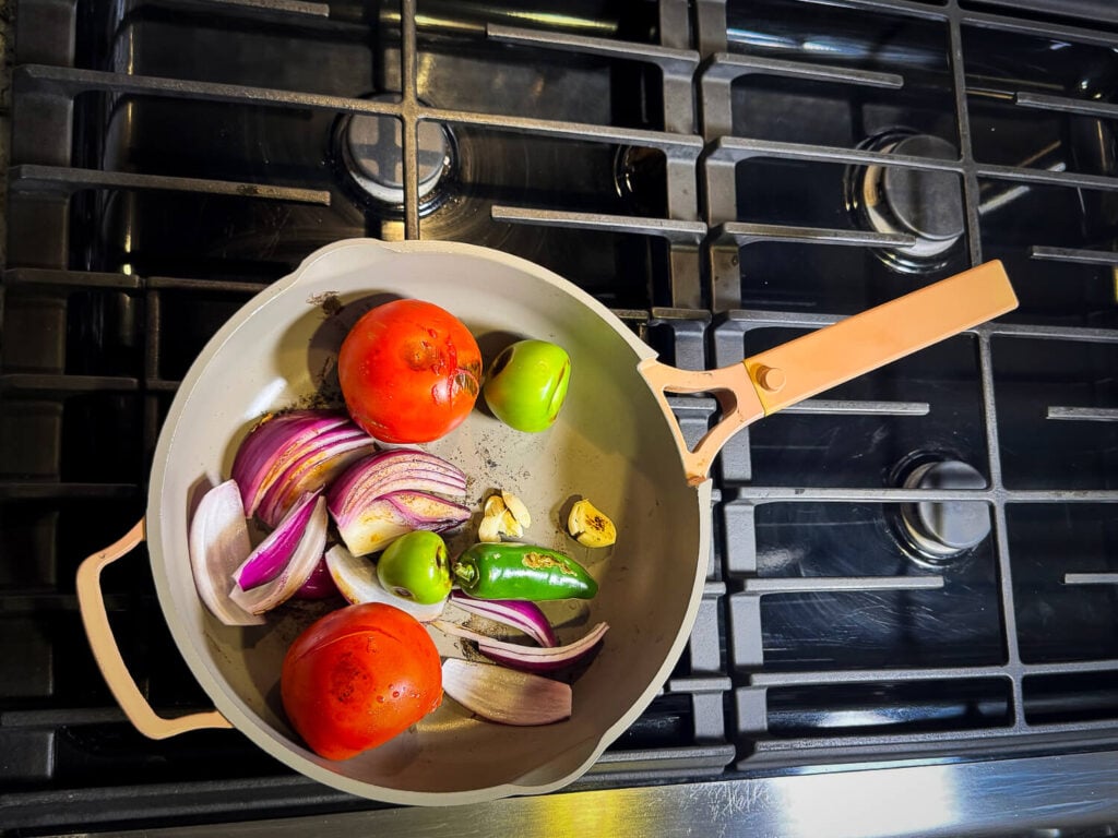 photo of tomatoes, tomatillos, garlic and onions in a non stick pan
