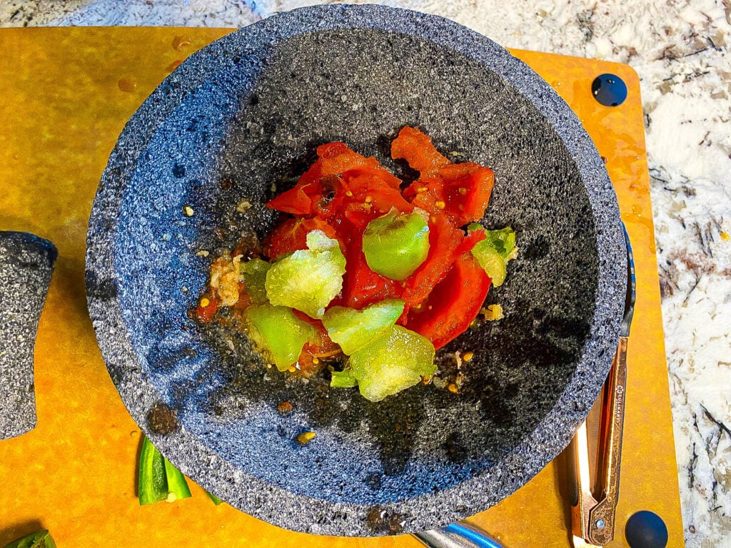 photo of tomatoes and garlic chopped up in a mortar and pestle
