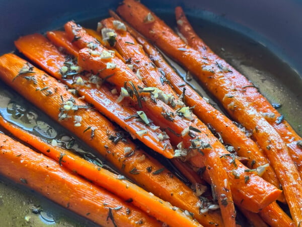 photo of honey roasted carrots in a gray bowl garnished with rosemary