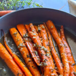 photo of honey roasted carrots in a gray bowl garnished with rosemary