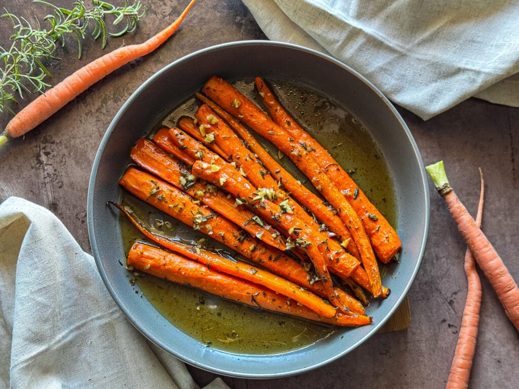 photo of honey roasted carrots in a gray bowl garnished with rosemary