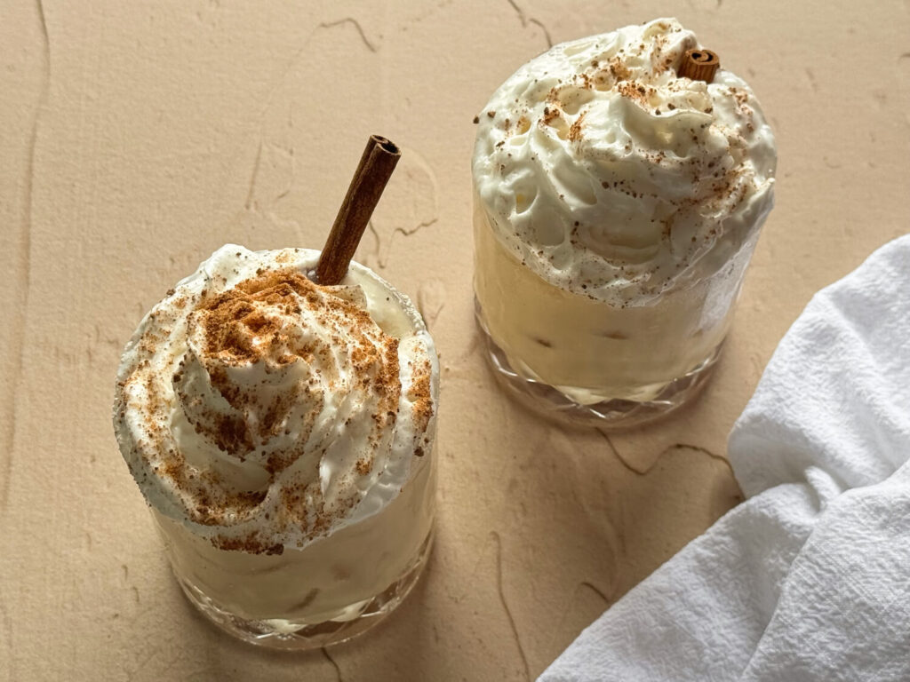 overhead shot of two glass of dairy free eggnog topped with dairy-free whipped cream