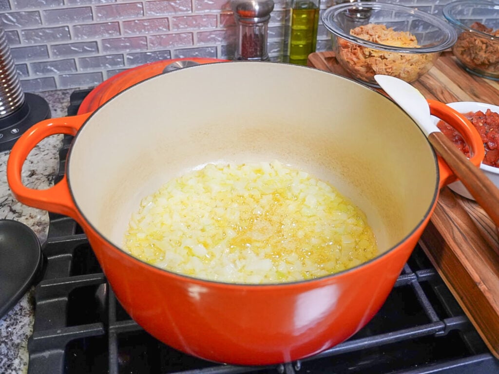 photo of onions cooking in butter in an orange dutch oven