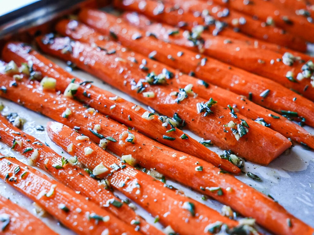 close up photo of carrots covered in olive oil garlic and rosemary