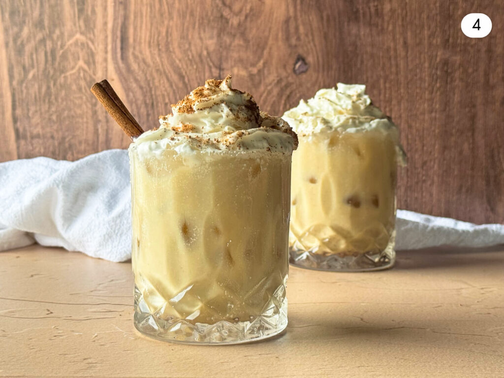 photo of two glasses of dairy-free eggnog topped with dairy-free whipped cream