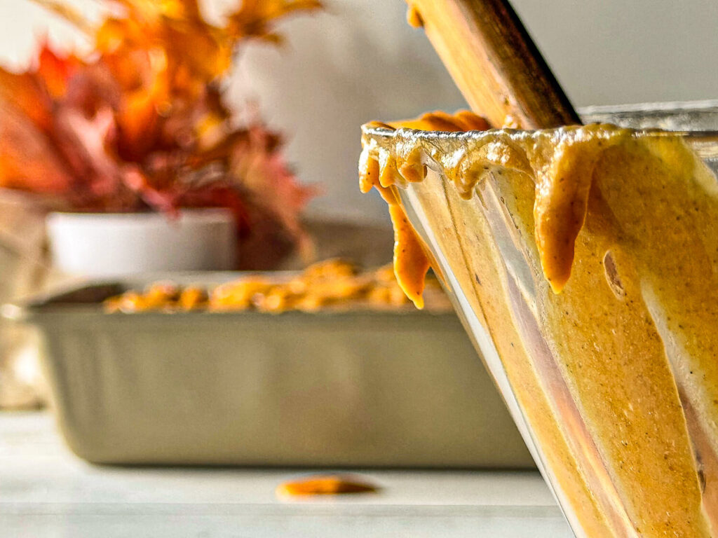 photo of pumpkin bread mix dripping out of a bowl