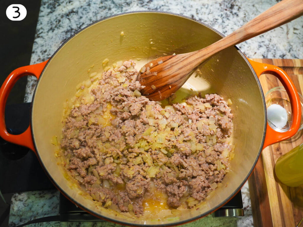 photo of ground hot Italian sausage being saut&eacute;ed in a Dutch oven