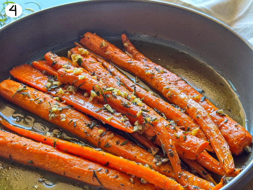 photo of honey roasted carrots in a gray bowl garnished with rosemary