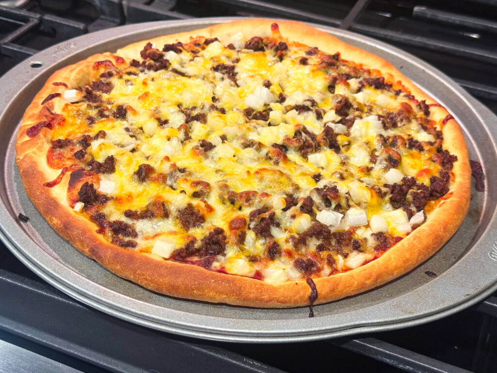 photo of taco pizza fresh out of the oven with ground beef, onions, and cheese