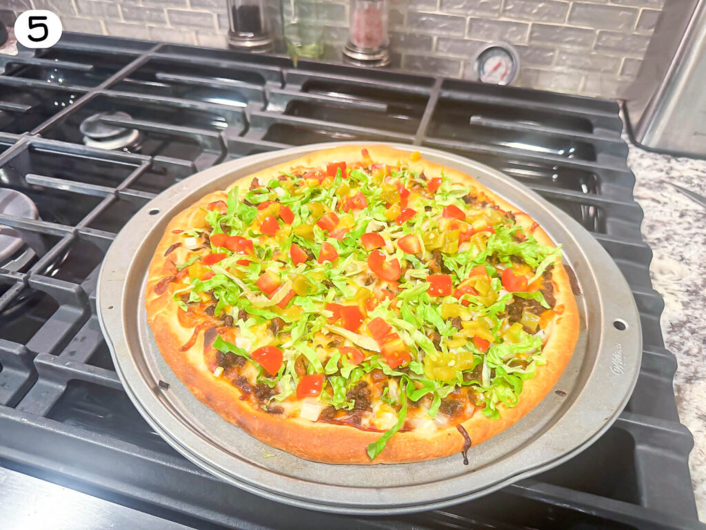 photo of taco pizza with lettuce and tomato on top