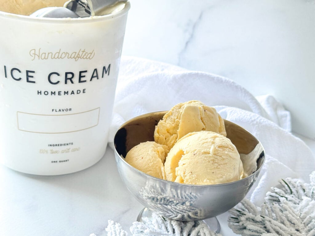 photo of Eggnog Ice Cream in a silver bowl next to a container of Ice Cream