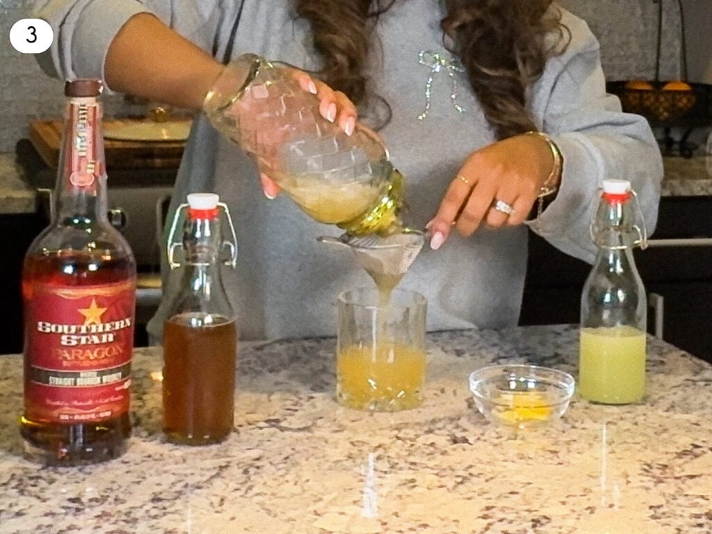 photo of straining Gold Rush Cocktail recipe through a strainer