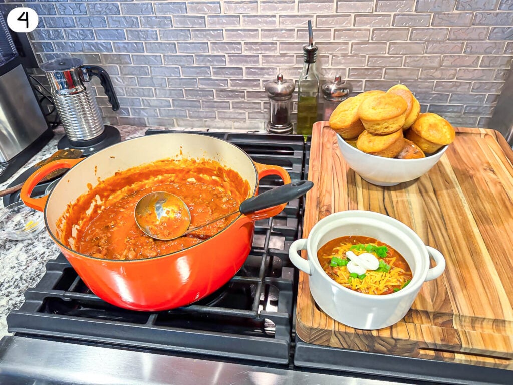 photo of a pot and bowl of chili on a stove with a basket of bread