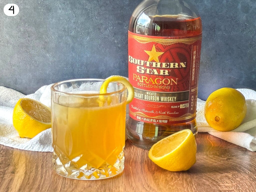 photo of Gold Rush Cocktail next to a bottle of bourbon