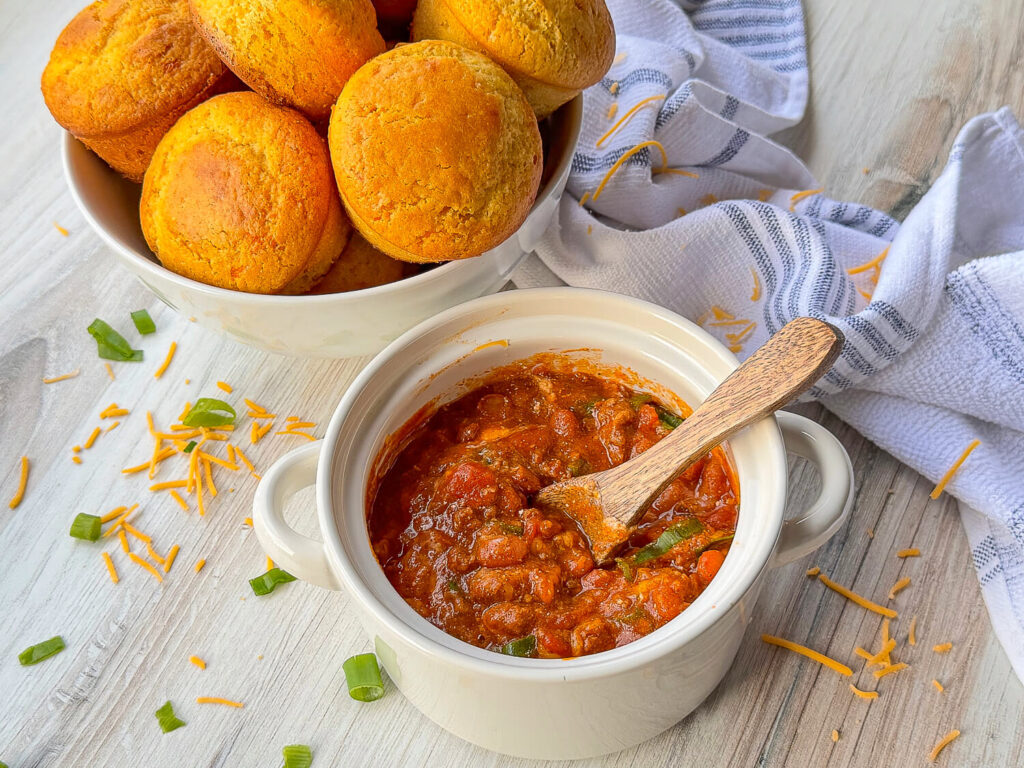 a bowl of chili next to a basket of cornbread