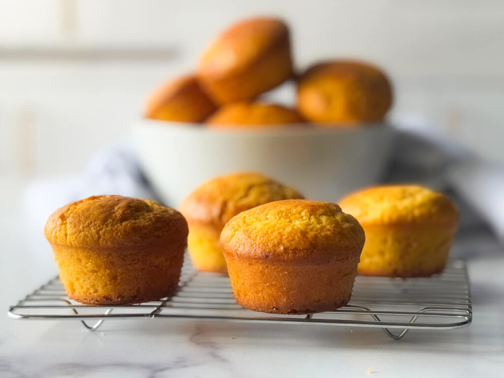 photo of Cornbread Muffins in focus on a wire cooling rack