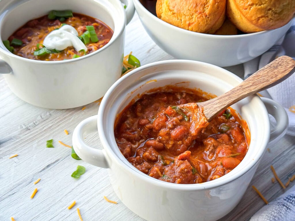 photo of two bowls of homemade chili next to a basket of cornbread