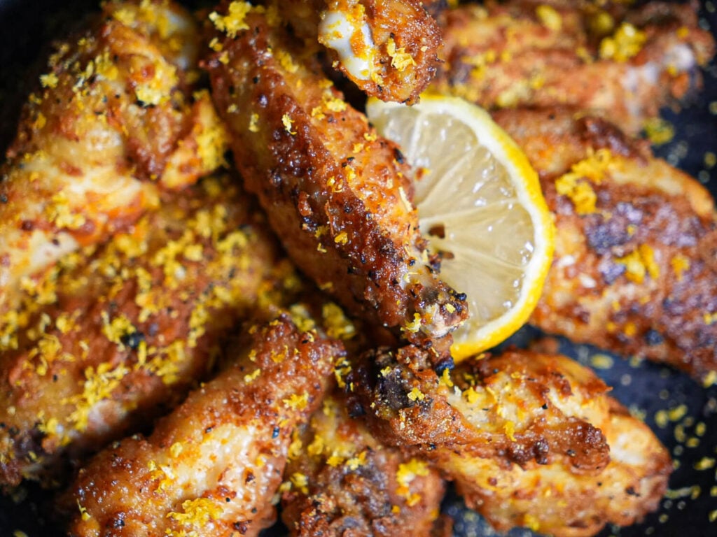 Photo of Air Fryer Lemon Pepper Wings with lemon zest and a lemon wedge