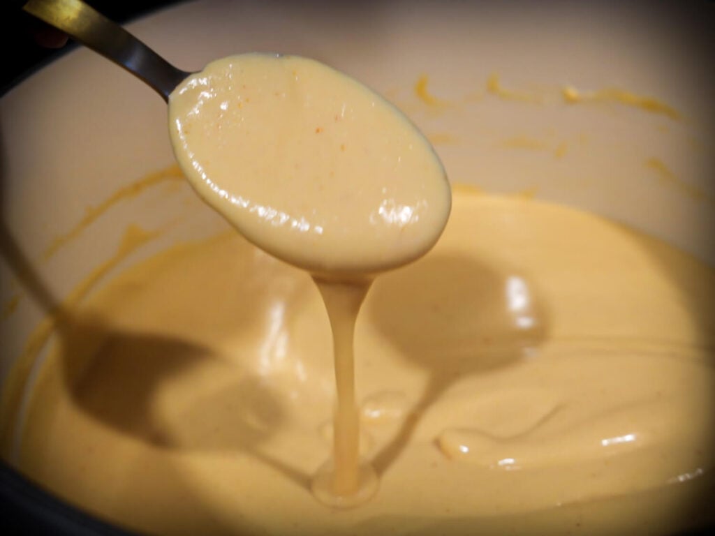 Close up photo of melted beer cheese dip falling off of a spoon