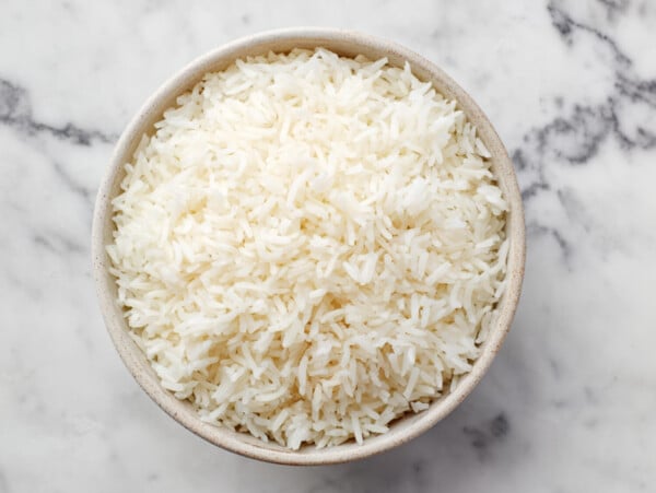 photo of cooked white rice in a tan bowl on a marble surface