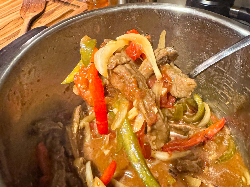 photo of pepper steak being scooped out of the slow cooker