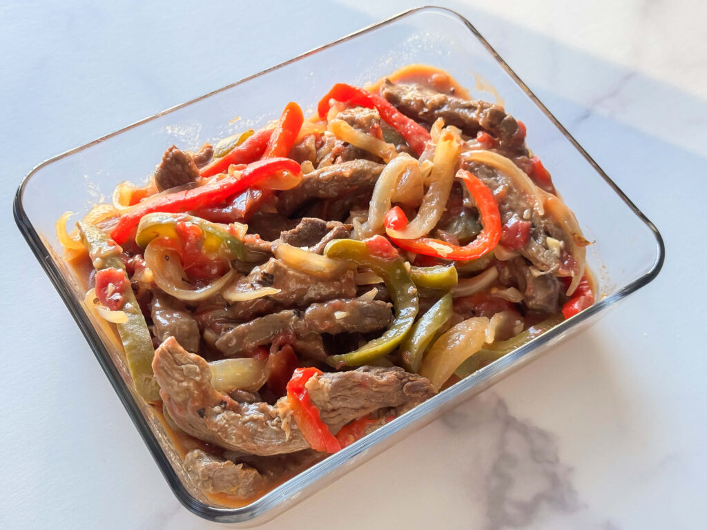 photo of slow cooker pepper steak in a glass storage container