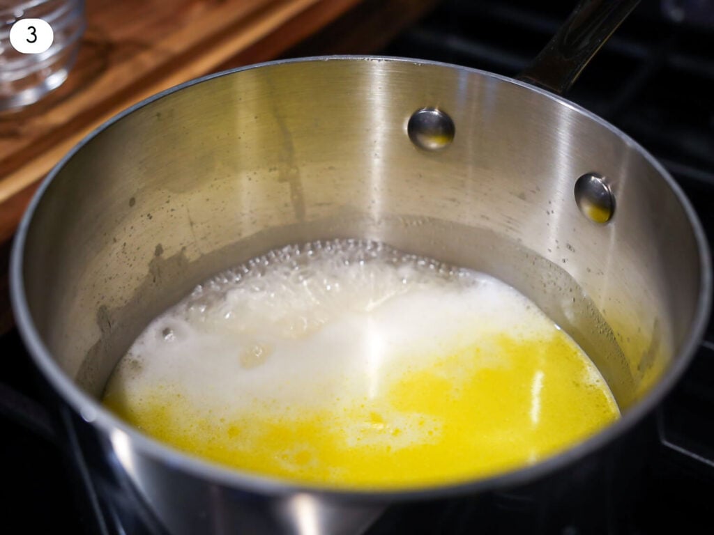 photo of white rice, water, and butter coming to a boil in a sauce pan