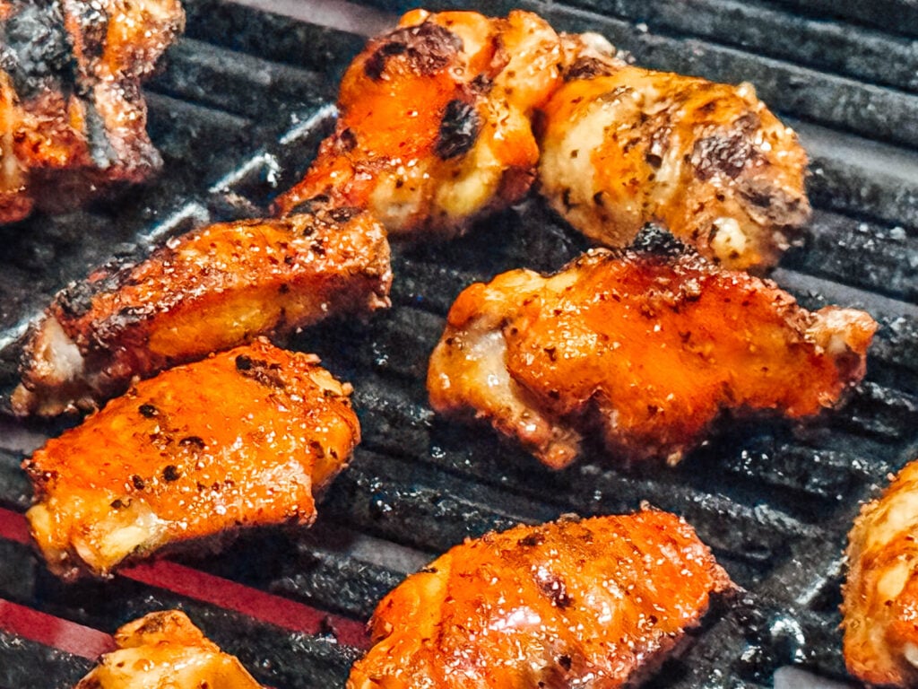 close up photo of cooked grilled chicken wings on a grill grate