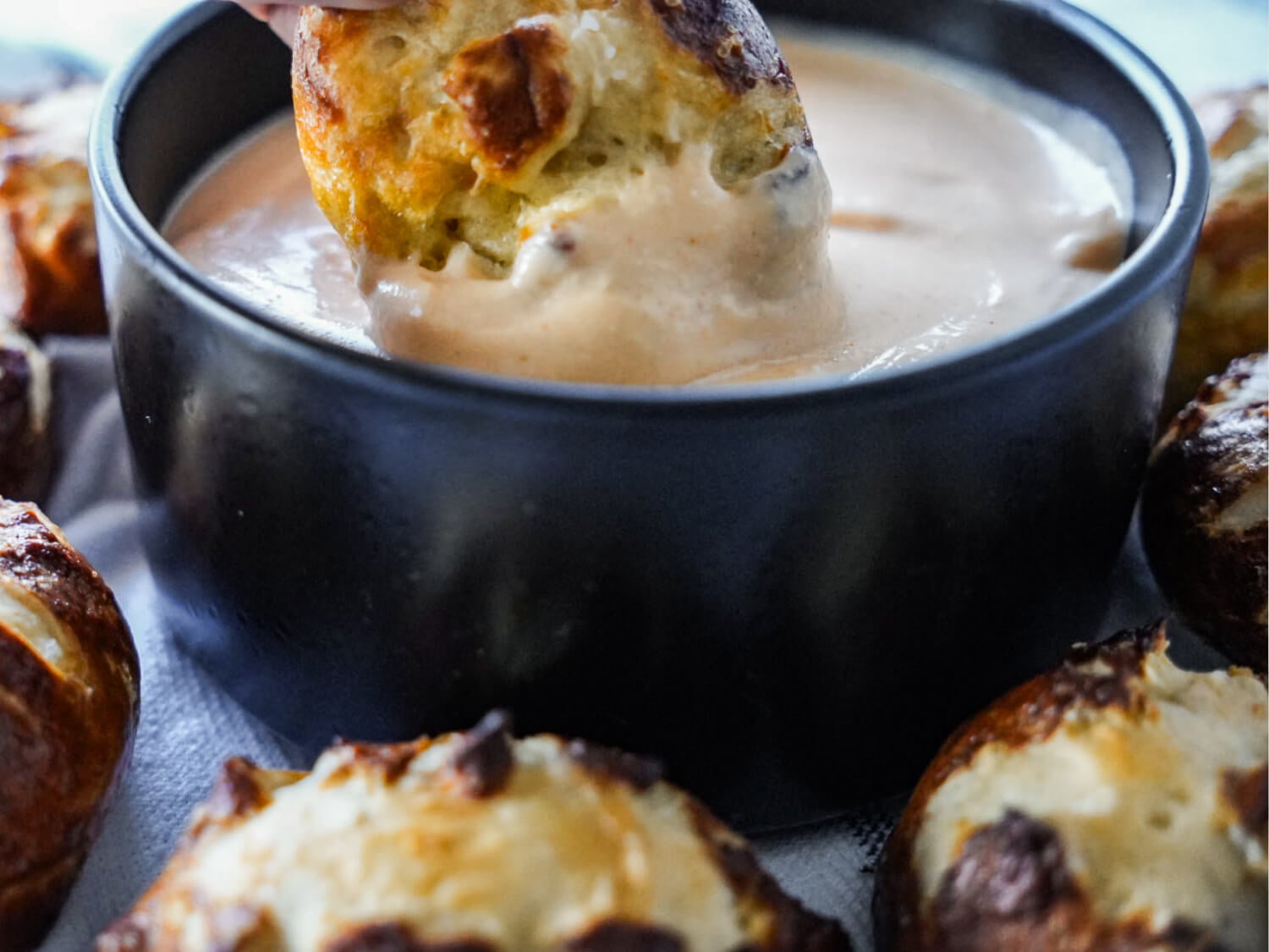 close up photo of pretzel being dipped in beer cheese dip