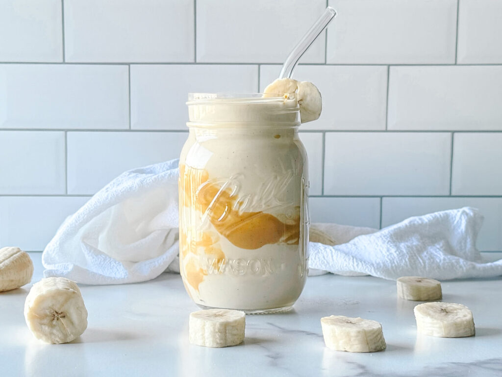 Photo of a peanut butter smoothie in mason jar surrounded by banana slices