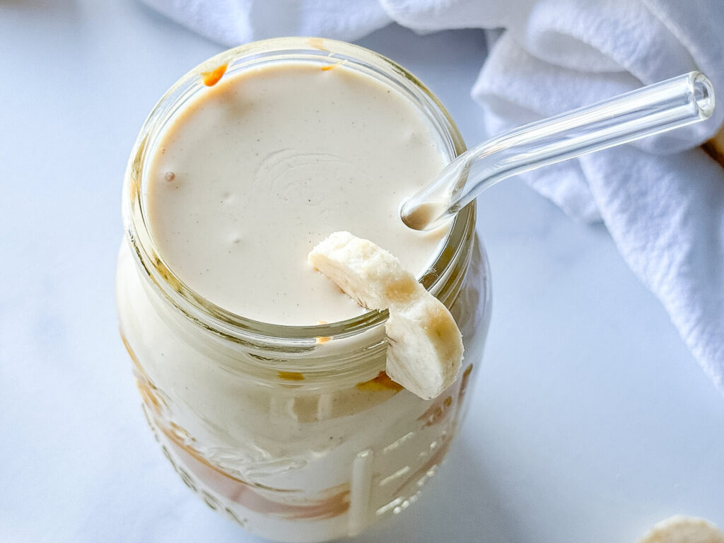Overhead photo of a peanut butter smoothie in a mason jar with a glass straw