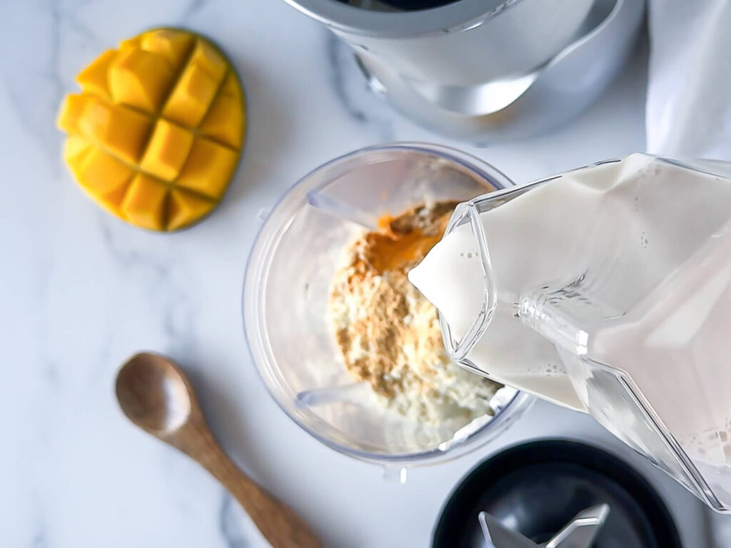overhead photo of almond milk being poured into a blender cup