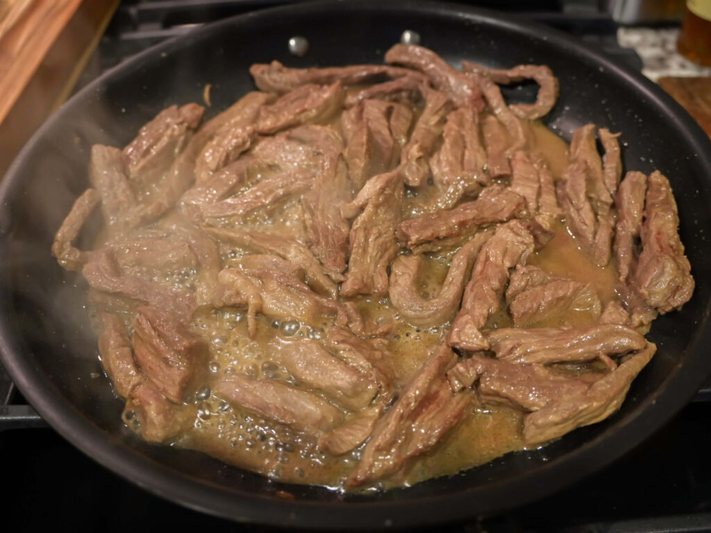 photo of strips of sirloin cooking in a nonstick pan
