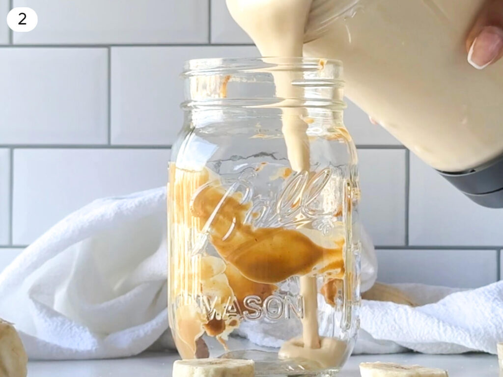 photo of peanut butter smoothie being poured into a serving glass after being blended