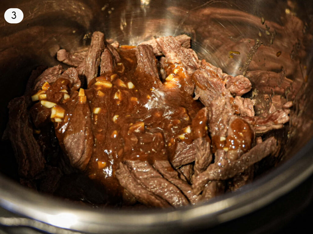 photo of garlic gravy sitting on top of cooked steak in the slow cooker
