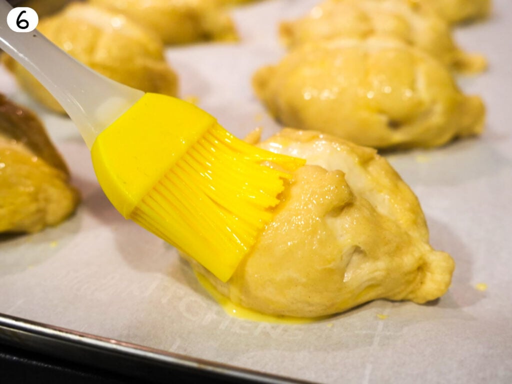 step 6 close up photo of egg wash being applied to dough
