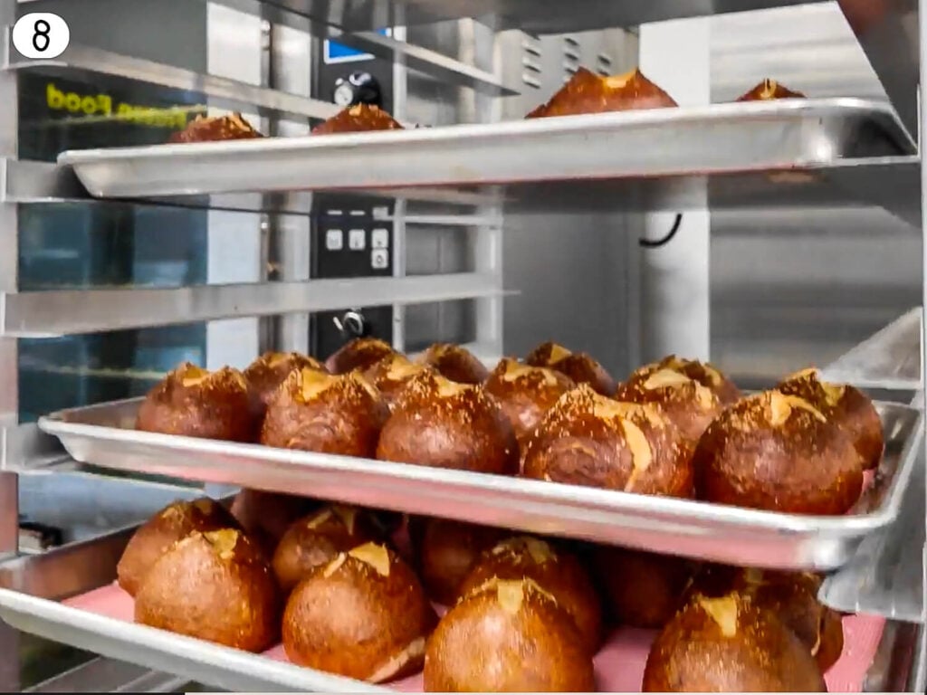 step 8 photo of baked pretzel buns on multiple trays from school
