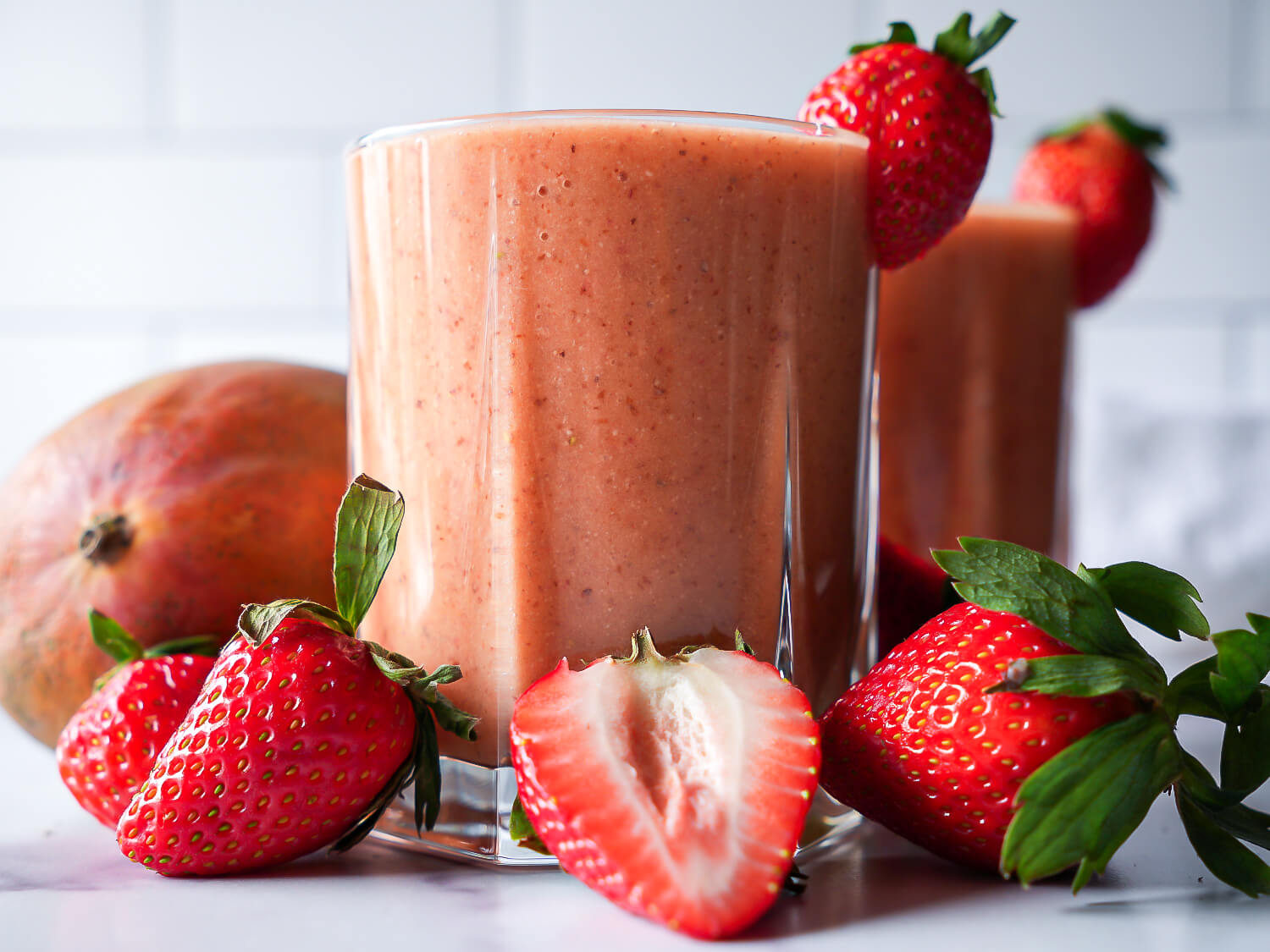 HERO - two strawberry mango smoothies surrounded by fruit
