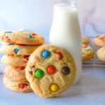 Photo of M&M cookies stacked next to a bottle of milk